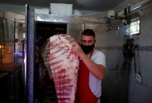 ブエノスアイレスの精肉店で、冷蔵庫から牛肉を取り出す店員