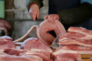 北京の精肉店で豚肉を切る様子