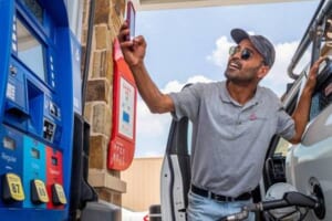 ガソリンの給油中、表示された価格をスマートフォンで撮影する男性