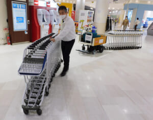 ショッピングカート運搬支援ロボットの実演を行うメーカーの従業員