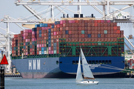 米カリフォルニア州オークランドのオークランド港で、コンテナ船の脇を航行する帆船